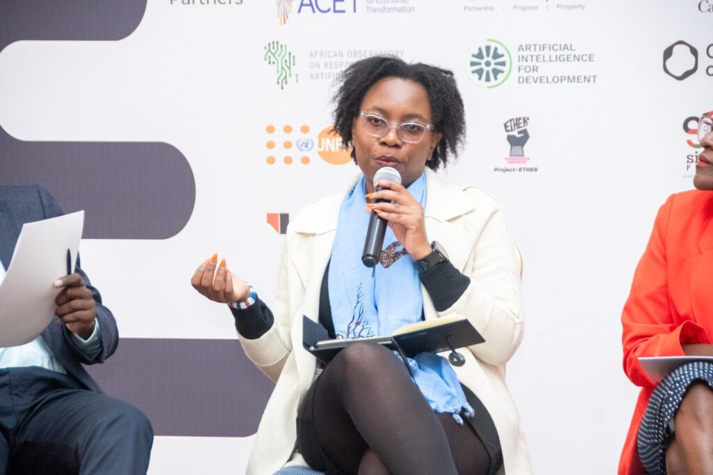 Florence is speaking into a microphone at the panel