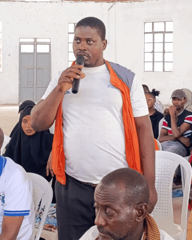 A VSLA member asking a question during the EDACR community meeting at Hola Social Hall, Tana River County.